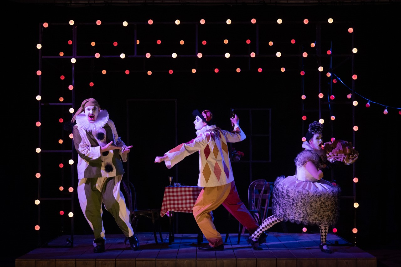 Three people dressed as clowns on stage performing