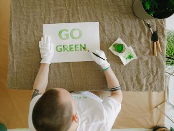 person printing go green words on a piece of paper in green