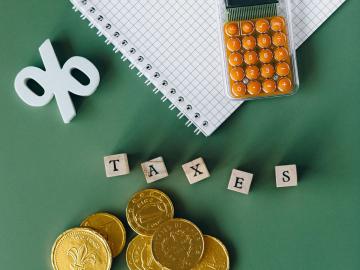 Image of a calculator, coins, a percentage sign and the word taxes