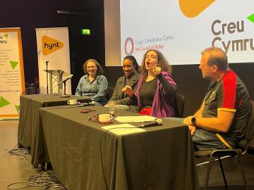 3 women and 1 man sitting as panel at Conference