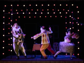 Three people dressed as clowns on stage performing