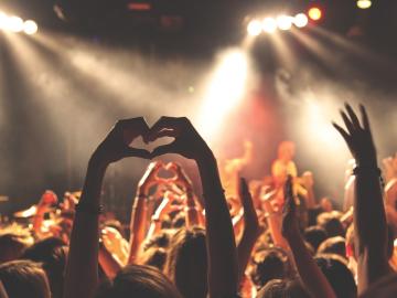 Audience members with arms in the air at a concert with bright lights