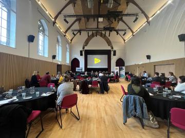 Image of people sat at tables at a Conference