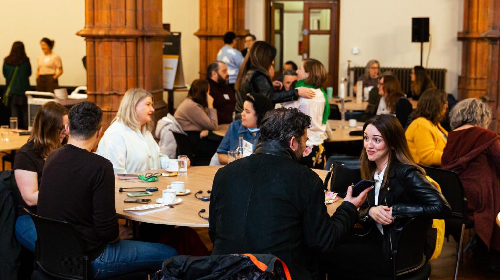 Group of people sat round table chatting at a conference