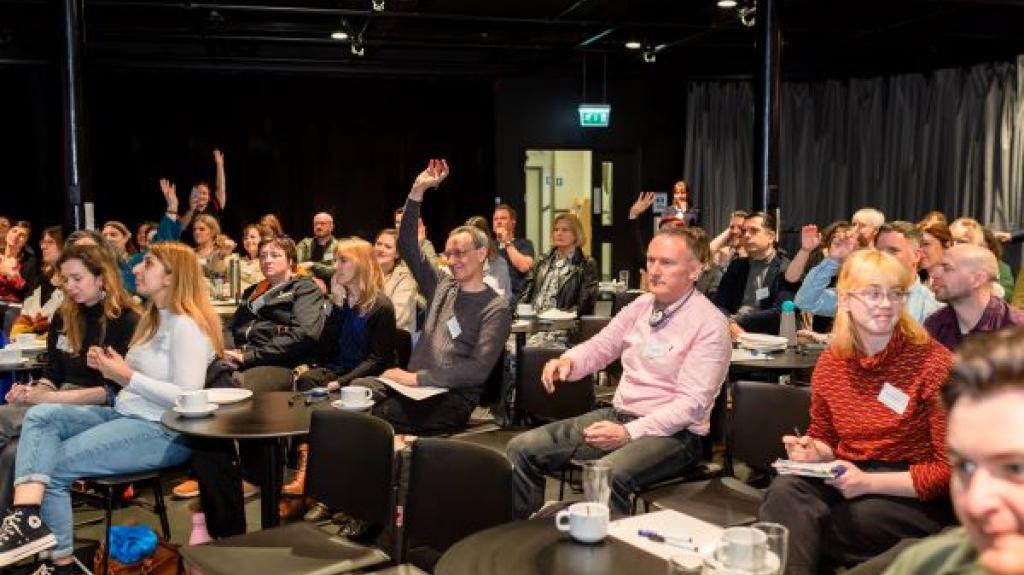 Image of people siting round tables at Creu Cymru Conference