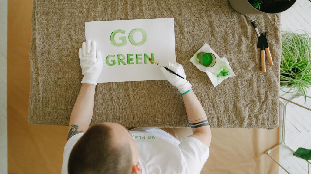 person printing go green words on a piece of paper in green