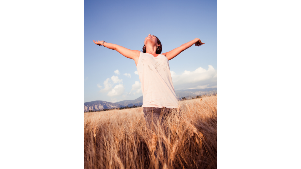 Woman standing in a field with her arms wide open