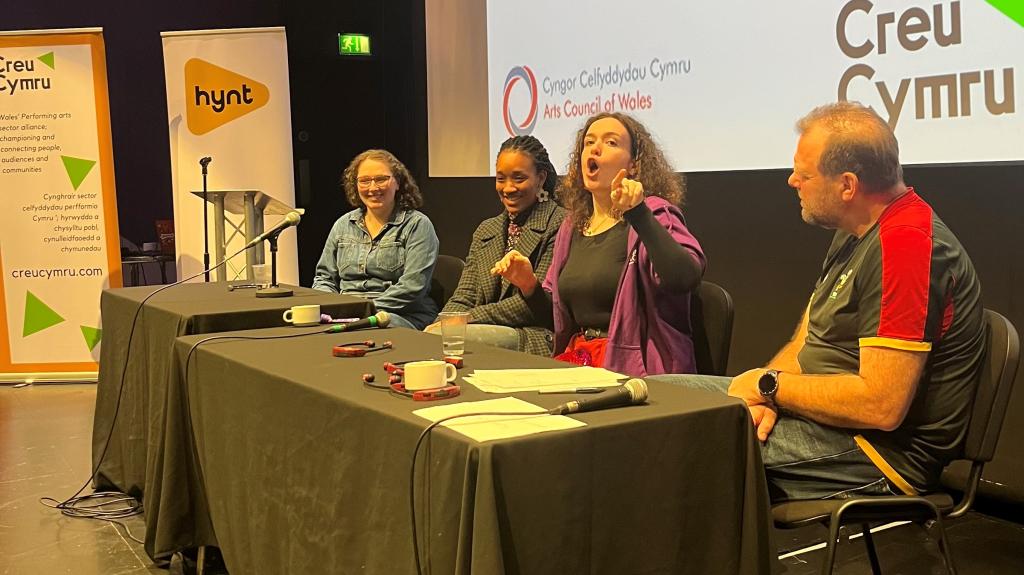 3 women and 1 man sitting as panel at Conference