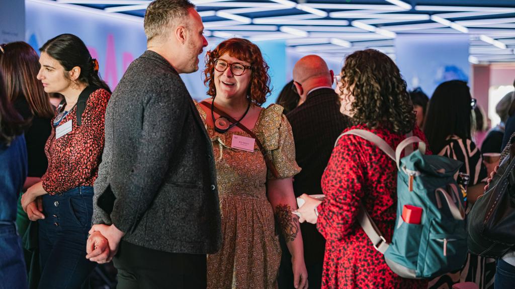 Image of people stood around talking and smiling